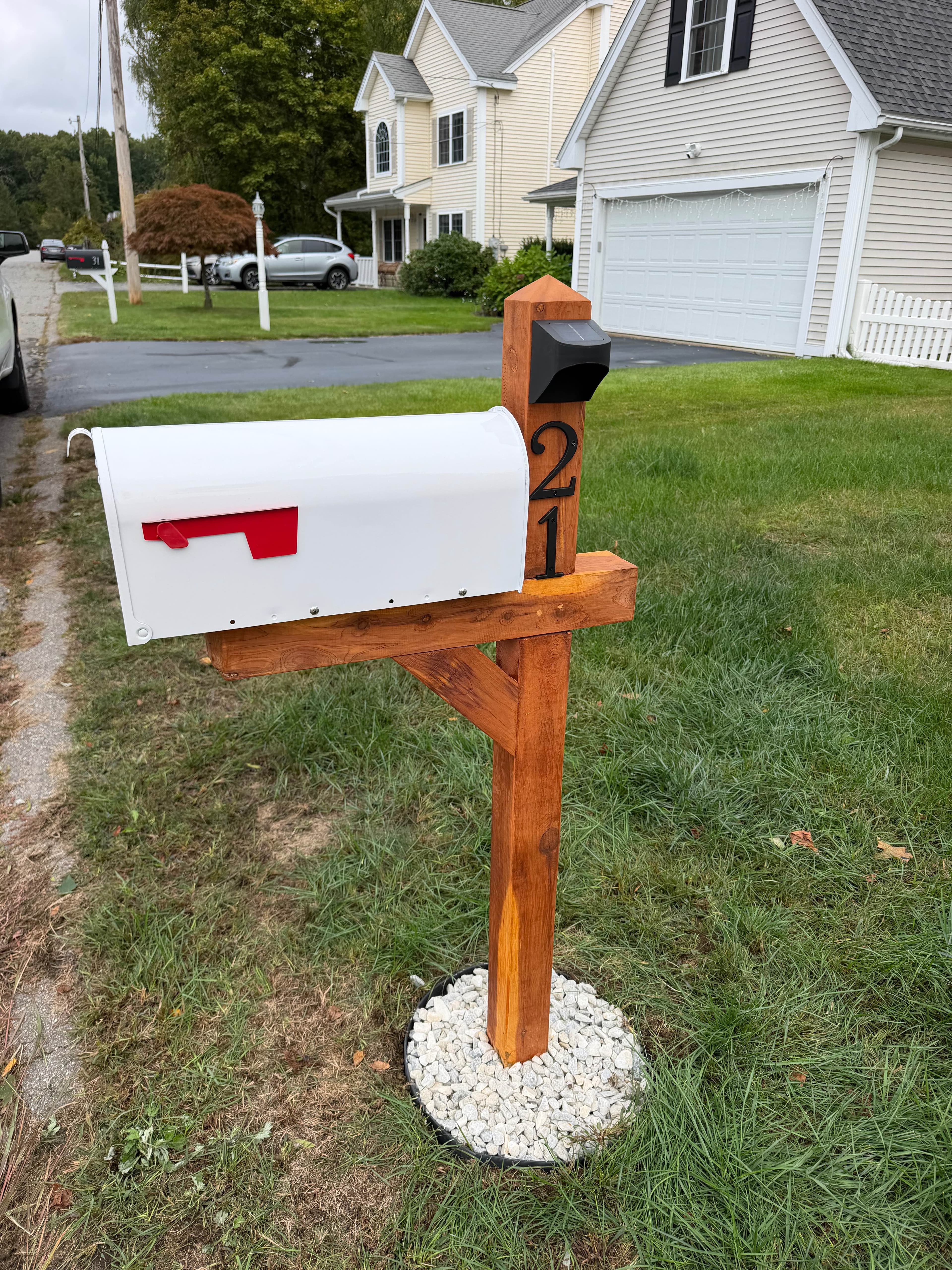 After: New cedar mailbox post with a white mailbox, house number 21, solar light, and a white stone base