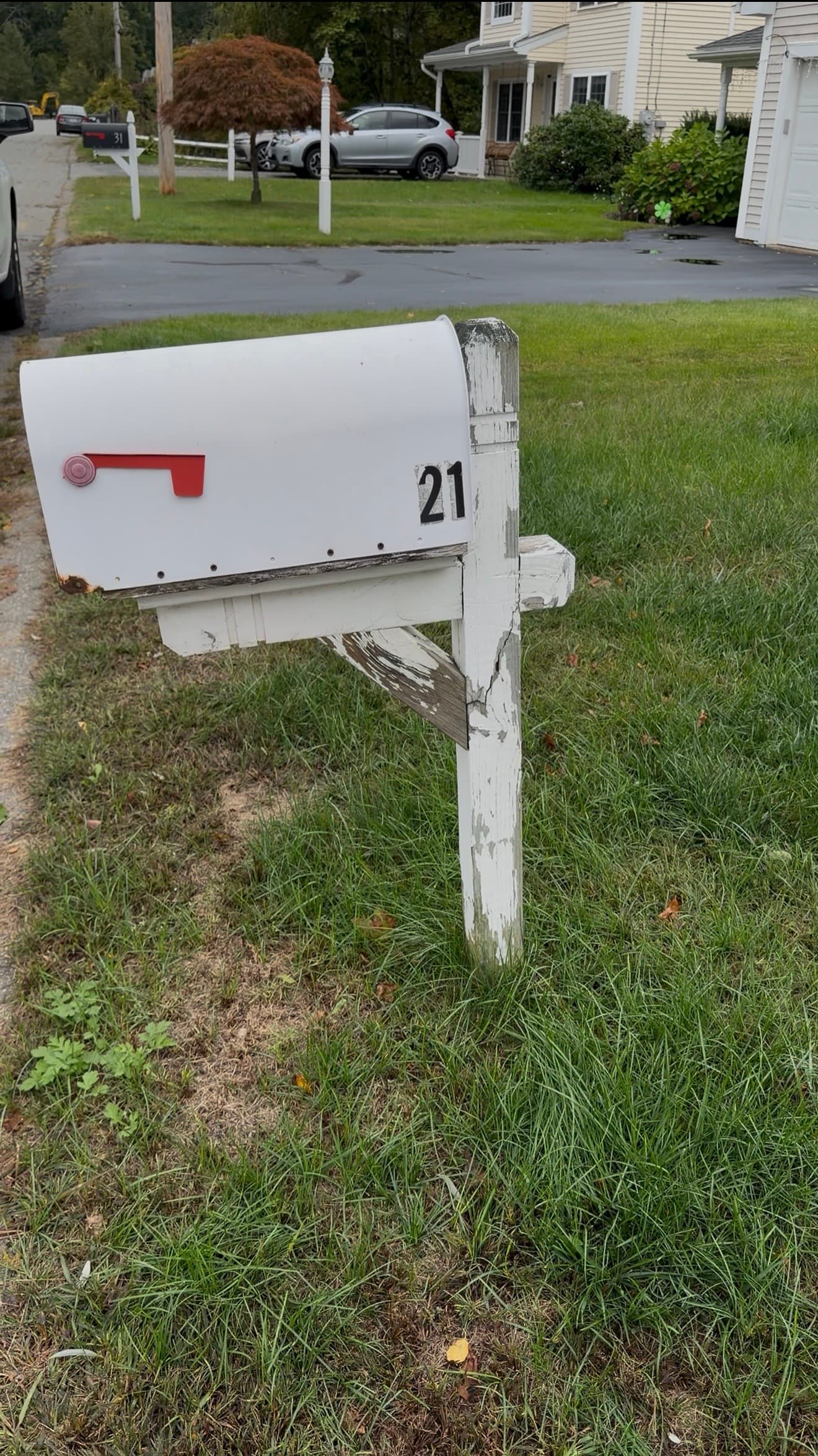 Before: Old white wooden mailbox post with peeling paint and a cracked post